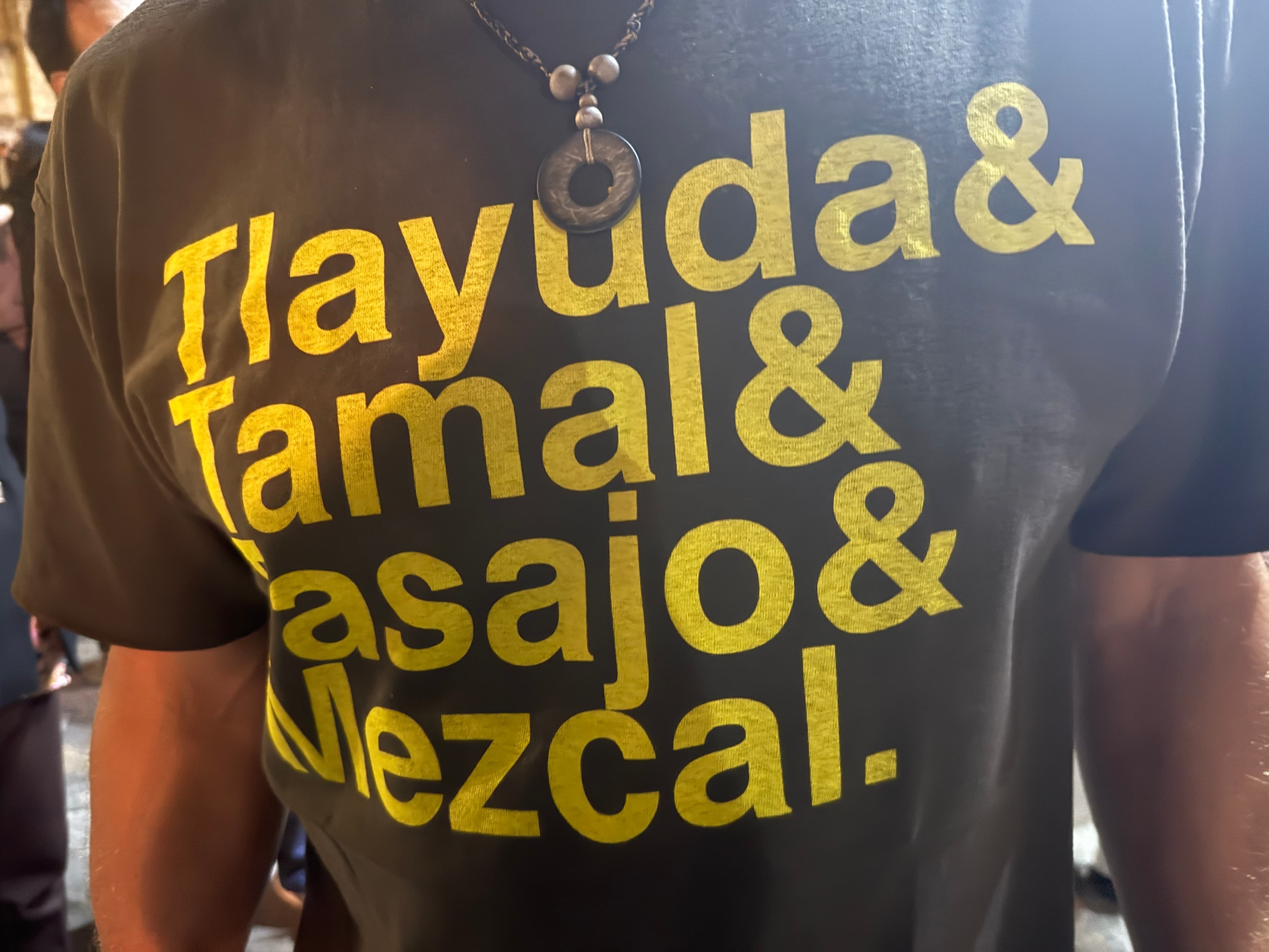 This shirt encodes belonging in written language - if you know the foods, you know the place. (You'd even know the occluded letter is "T", for "Tajajo", a type of beef.